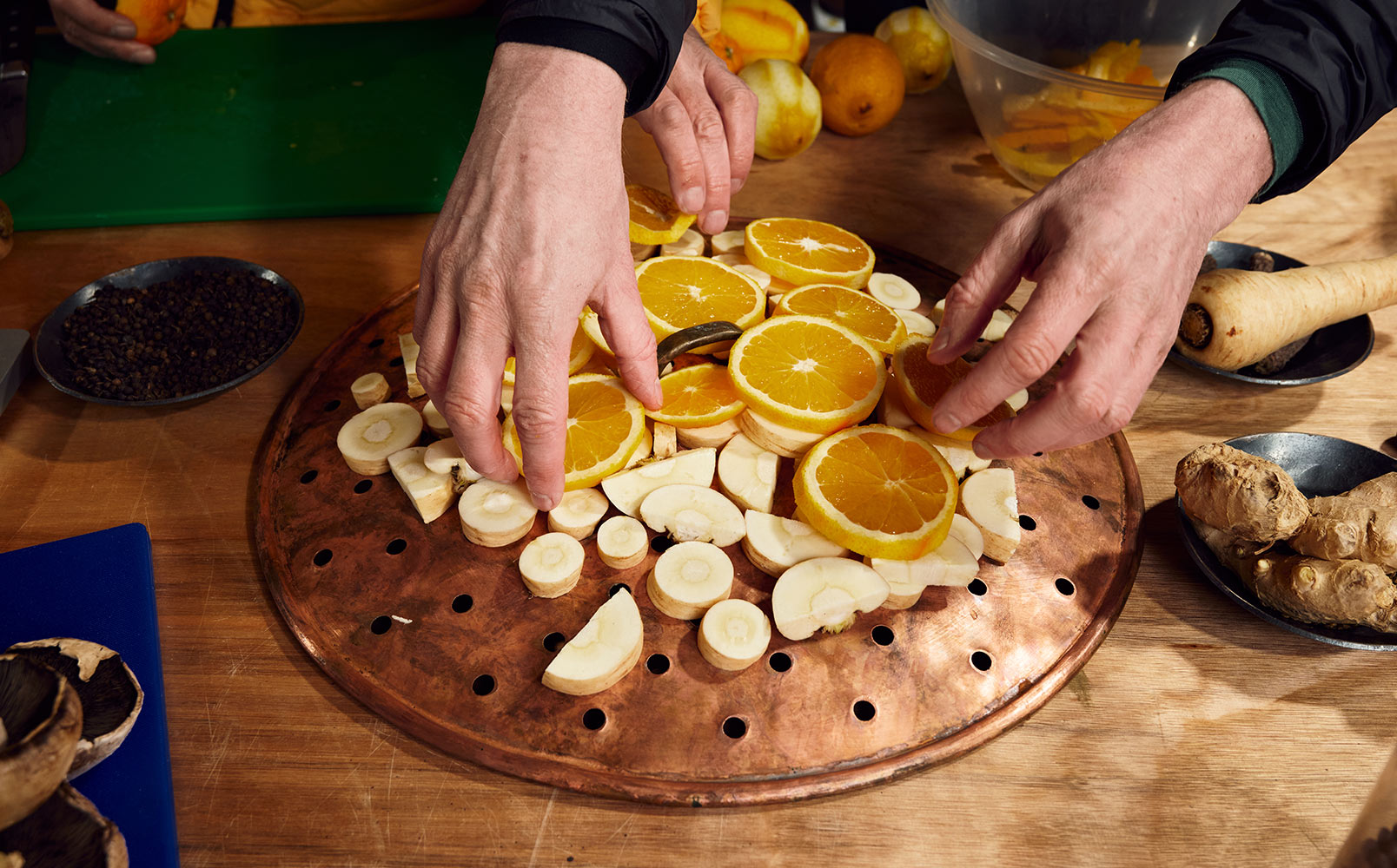 Hugh and James' hands arranging the botanicals orange and parsnip slices on a brass board