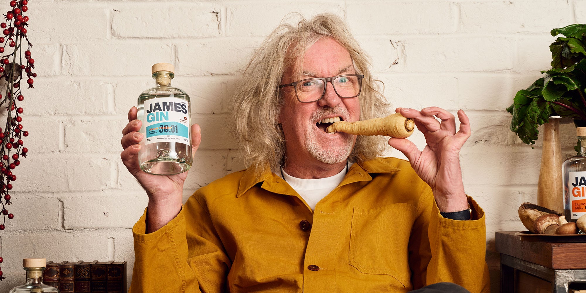 James May in the shed taking a bit into a parsnip and holding a bottle of Asian Parsnip