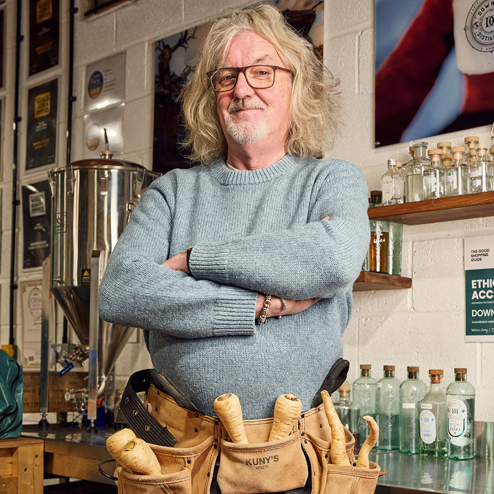 James May in his shed with his arms crossed wearing a tool belt filled with parsnips