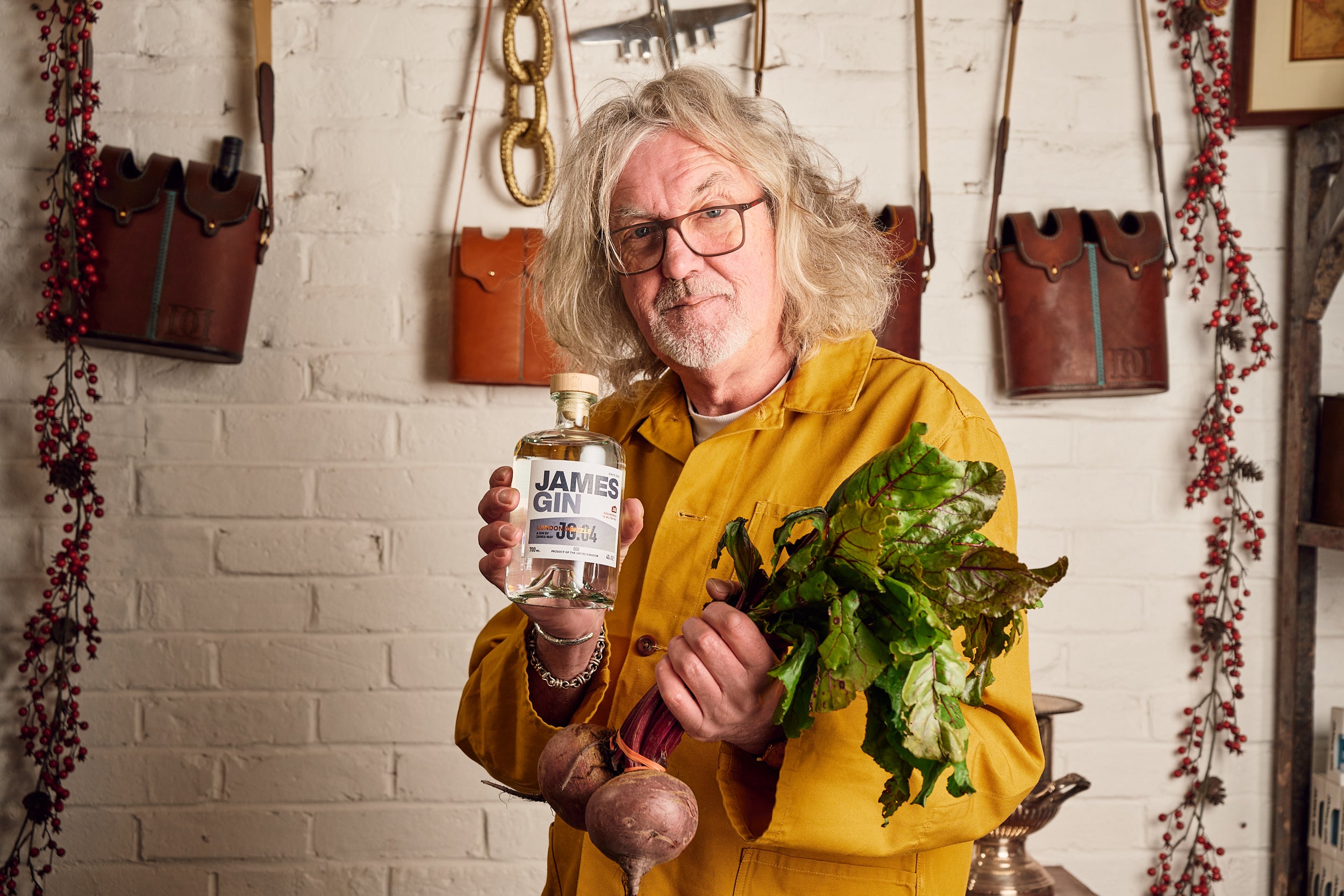 James May inside the shed holding a bottle of London drizzle and a bunch of beetroot