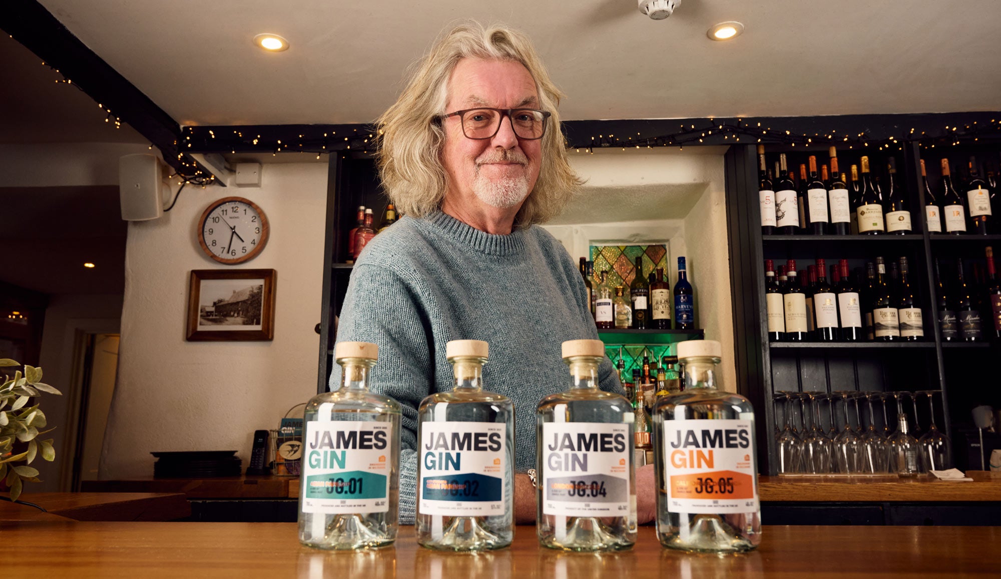 James May in his pub standing at the bar behind his range of gins